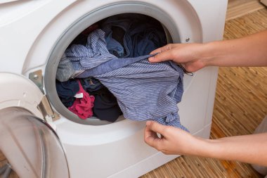 Kadın çamaşır makinesinden çamaşır çıkarır