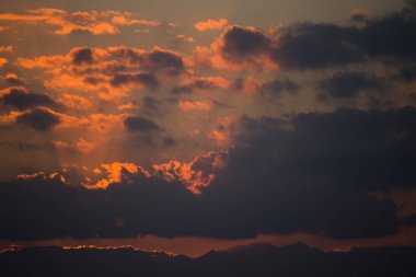 İtalya 'nın Sicilya kentindeki Cefalu şehrinde gün batımında güneş ışınları denizin üzerinde bulutları delip geçer.
