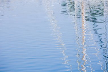 Denizlerdeki yat ve gemilerden gelen beyaz direklerin yansıması.