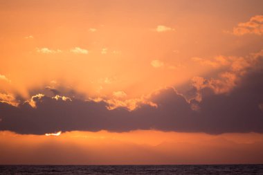 İtalya 'nın Sicilya kentindeki Cefalu şehrinde gün batımında güneş ışınları denizin üzerinde bulutları delip geçer.