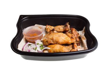 Beyaz arka planda izole edilmiş plastik bir kutuda sebzeli tavuk kebabı.