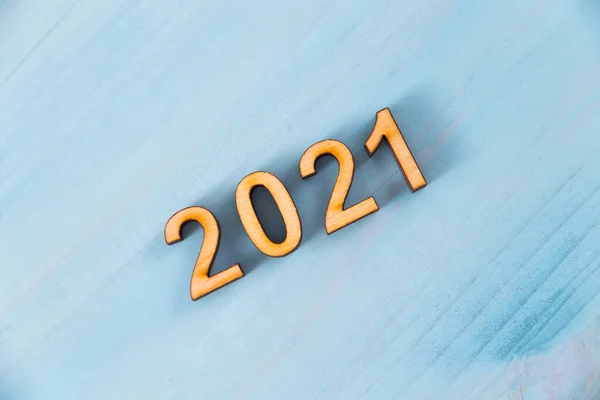 The number 2021 is made of wooden letters on a blue natural background made of wooden boards