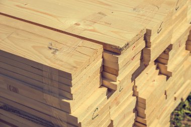 Kenarlı tahta, güneşte caddede uzanan bir yığın yapı malzemesi, bir bahçe arsasına ev inşa etmek.