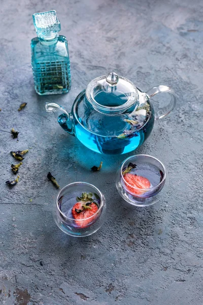 Mavi asya çayı 2 fincan ile çaydanlık. Çay fincanlarında strowberries. Kahverengi dokular taş arka plan.  