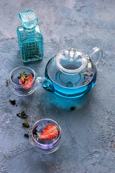 Mavi asya çayı 2 fincan ile çaydanlık. Çay fincanlarında strowberries. Kahverengi dokular taş arka plan.  