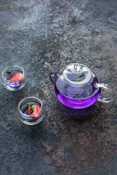 Mavi asya çayı 2 fincan ile çaydanlık. Çay fincanlarında strowberries. Kahverengi dokular taş arka plan.  