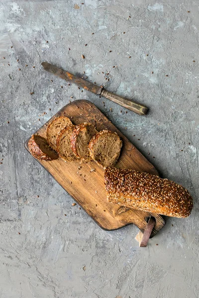 Kesme Tahtasında tahıl baget. dilimlenmiş, gri taş doku arka plan üzerinde vintage bıçak. Üstte görüntü