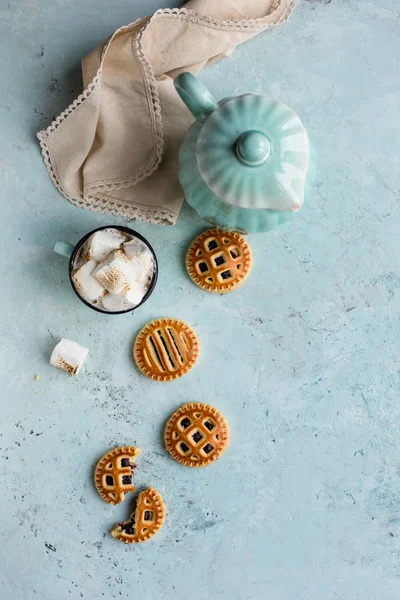 Vintage mavi çaydanlık, marshmallow, peçete ve mavi dokulu arka plan üzerinde kurabiye ile sıcak çikolata Kupası. Vintage dekorlar. Üstte görüntü.