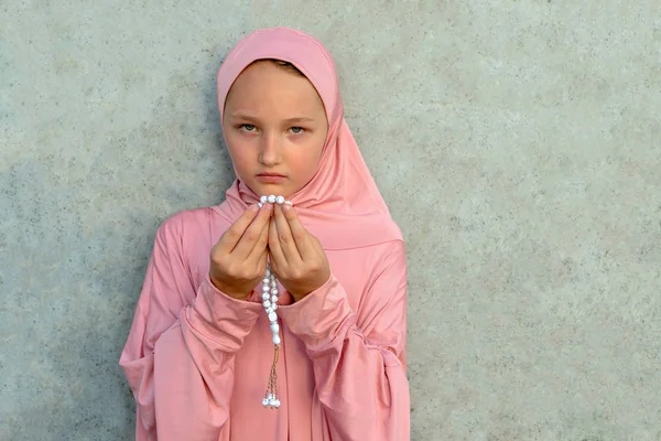 Ein Kind im rosafarbenen Hijab mit einer Perle in der Hand und Kopierraum. Menschen religiöser Lebensstil Konzept. — Stockfoto