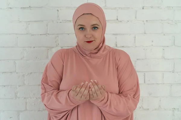 Weiße Frau mit blauen Augen in rosa Hijab betet auf weißem Hintergrund. Menschen religiöser Lebensstil Konzept — Stockfoto