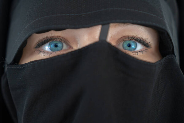 Молодая женщина с голубыми глазами в черном. Девушка в парандже. Концепция религиозного образа жизни
.