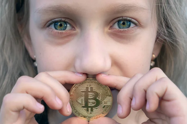 Dziewczyna zbliżenie z zielonymi oczami trzyma monetę Bitcoin w ustach. Koncepcja łatwego inwestowania i handlu Bitcoin — Zdjęcie stockowe