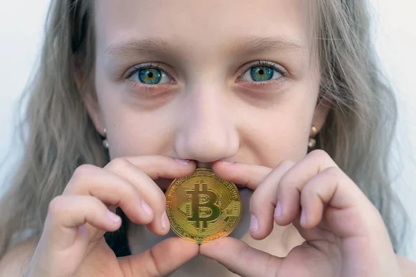 Dziewczyna z zielonymi oczami trzyma monetę Bitcoin w ustach. Koncepcja łatwego inwestowania i handlu Bitcoin. — Zdjęcie stockowe