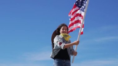 Bağımsızlık Günü. Vatansever bir bayram. Parlak güneşli bir günde Amerikan bayrağı ile siyah uzun saçlı güzel mutlu kız. ABD 4 Temmuz'u kutladı.