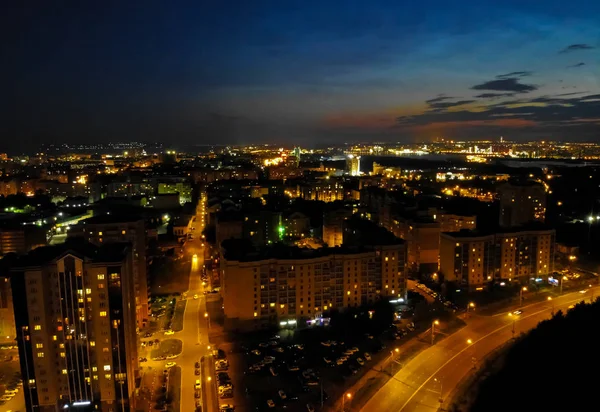 Flight on drone above night city with asphalt city roads, residential buildings and car traffic at night. — Stock Photo, Image