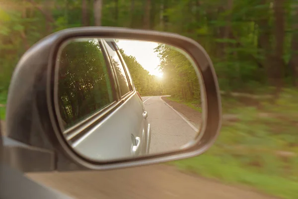 Landscape in the sideview mirror of a car , on road countryside. The sun is shining