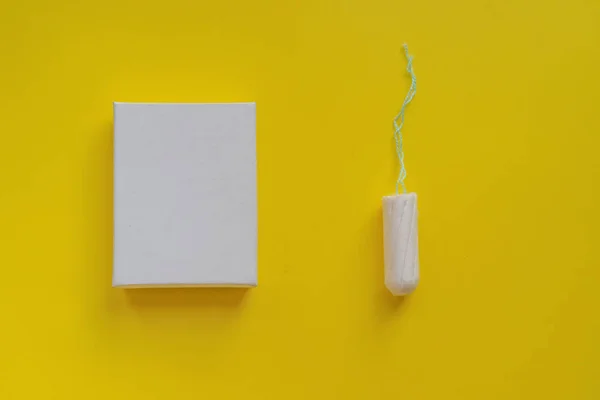 Concept menstruel. Protection hygiénique des femmes. tampon en coton dans une boîte blanche sur fond jaune. Espace de copie et maquette — Photo