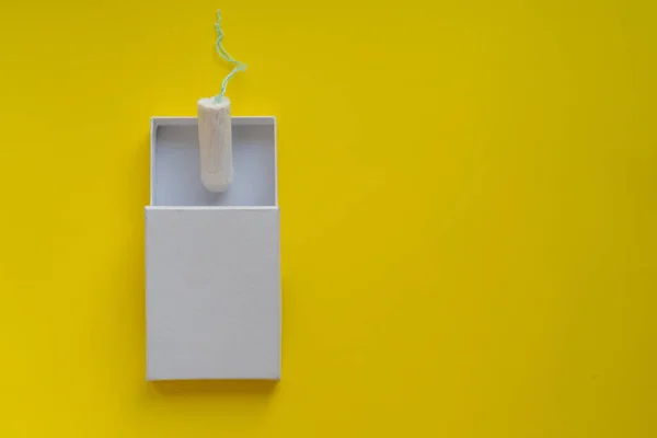 Concept menstruel. Protection hygiénique des femmes. tampon en coton dans une boîte blanche sur fond jaune. Espace de copie et maquette — Photo