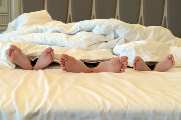 Le gambe dei bambini sporgono da sotto la coperta. Le ragazze si rilassano in hotel. Concetto di viaggio con bambini — Foto Stock