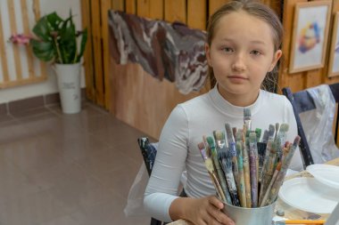 Kızın elinde farklı renk fırçalar bir dizi. Çocukları çizmek için sanat okulunun iç. Yaratıcılık ve insan kavramı.