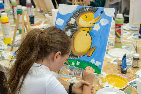 Красивая девушка с кисточкой в руке. Креативная девочка-подросток рисует на мольберте. Интерьер художественной школы для рисования детей. Концепция творчества и людей . — стоковое фото