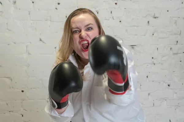 The girl in boxing gloves is looking at the camera. Emotions anger and aggression. Feminism and femininity. — Stock Photo, Image