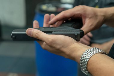 Atış poligonunda Glock silah modelini kullanarak ateş etmeye tenefereden bir adam. Ateş glock el silahı. adamın elleri bir tabanca şarjör yükleme. adam tabanca klibi yükler