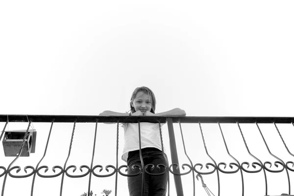 Девятилетняя девочка стоит у железного забора. Фото взято из bel — стоковое фото
