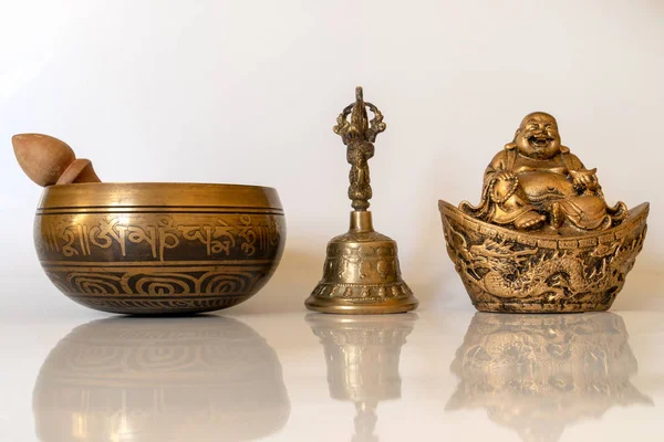 Singing bowl,  Figurine Cheerful Hotei  and golden bell close-up