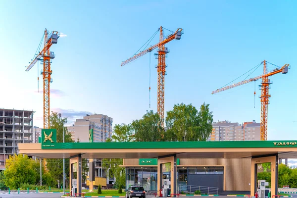 Rusia, Kazan - 7 Juli 2019: tiga derek Konstruksi dan bangunan yang sedang dibangun melawan langit biru. tiga Industrial Crane beroperasi dan mengangkat beton blok terhadap langit biru. Terdekat adalah g — Stok Foto