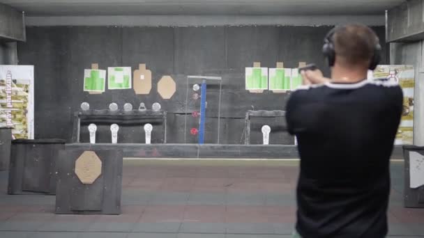 Rusko, Tatarstán, 23. června 2019. Člověk na střelbě v akci s Glock 19, pohled zezadu za držení pistole, která se zaměřuje od kamery s mělkou hloubkovou hloubku. — Stock video