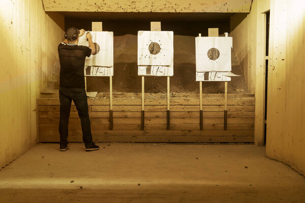 A man shooter hangs a paper target on a dash. Toned.