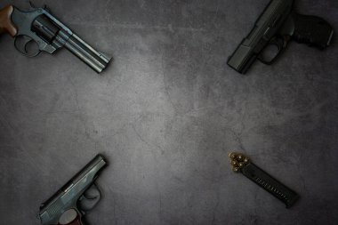 Cepheye ateşli silahlar bırakıldı. Üç tabanca, gri beton arka planda yakın plan fişekler. Boşluğu kopyala