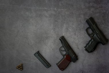 Cepheye ateşli silahlar bırakıldı. Üç tabanca, gri beton arka planda yakın plan fişekler. Boşluğu kopyala