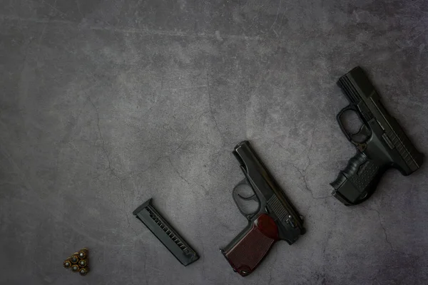 Firearms laid out along the line. Three guns pistols, cartridges close-up on a gray concrete background. copy space — Stock Photo, Image