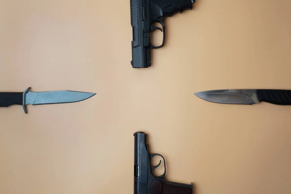Lőfegyverek egy kör mentén. Három pisztoly, katonai kések közelről, semleges bézs háttérrel. másolás helye — Stock Fotó