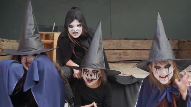 Cztery małe dziewczynki przebrane za czarownice, zombie, szkielet i makijaż wyglądają onieśmielająco przed kamerą. Zwolniony ruch. — Wideo stockowe
