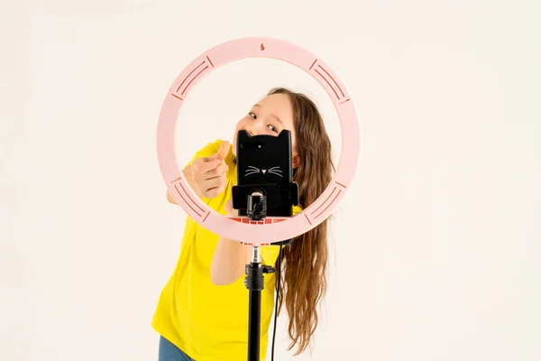 Seorang gadis remaja menari dan syuting video. Selfie. Ponsel dipasang pada tripod dan lampu cincin bersinar. — Stok Foto