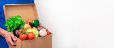 Beyaz arka planda mavi üniformalı taze sebze teslimatçısı. Web sayfası afişi için fotoğraf