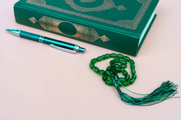 Μουσουλμανική ισλαμική πίστη έννοια Κοράνι βιβλίο, πράσινο στυλό για το γράψιμο, πράσινο κομπολόι σε ουδέτερο μπεζ φόντο. διάταξη και χώρος για κείμενο — Φωτογραφία Αρχείου