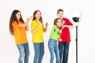 Bir grup çocuk blogcu telefonda video çekiyor. Selfie 'ler. Telefon, üç ayaklı modern bir lambaya monte edilmiştir..