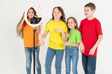Bir grup çocuk blogcu telefonda video çekiyor. Selfie 'ler. Telefon, üç ayaklı modern bir lambaya monte edilmiştir..