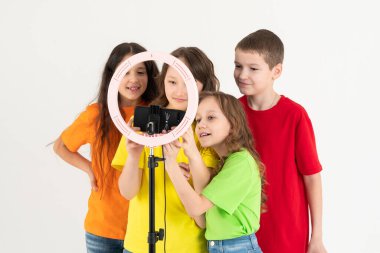 Üç genç kız ve bir oğlan gülümsüyor ve bir video çekiyor. Selfieler. Telefon bir tripoda monte edilir ve yüzük lambası parlar..