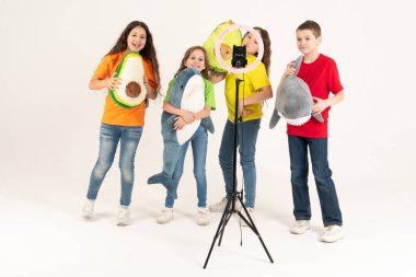 Bir grup çocuk blogcu telefonda video çekiyor. Selfie 'ler. Telefon, üç ayaklı modern bir lambaya monte edilmiştir..
