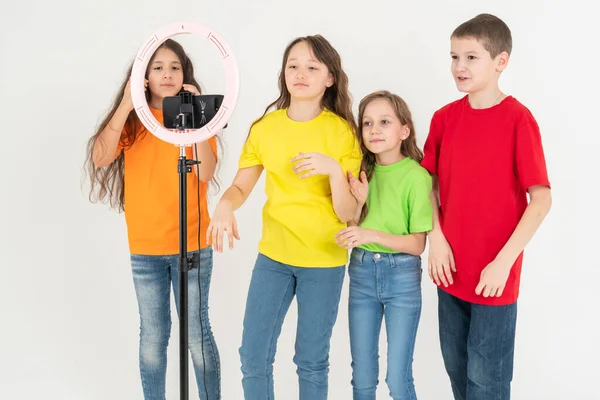 Un grupo de niños blogueros filman videos por teléfono. Selfies El teléfono está montado en una moderna lámpara redonda con un trípode . —  Fotos de Stock