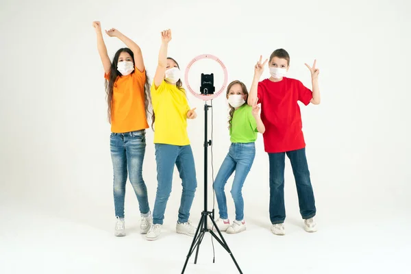 Los niños bailan positivamente con máscaras médicas. El concepto de aprendizaje a distancia durante una pandemia. Positivo. Movimiento y deporte . —  Fotos de Stock