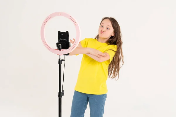 Una adolescente baila y filma un video. Selfies. El teléfono está montado en un trípode y la lámpara del anillo brilla —  Fotos de Stock