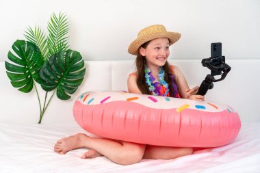 Küçük kız blogcu ev karantinasında tatil taklidi yapıyor ve telefonda video çekiyor. Ev turizmi. Turizm sektöründe Coronavirus durumu. Karantina. Evde kal. Tecrit