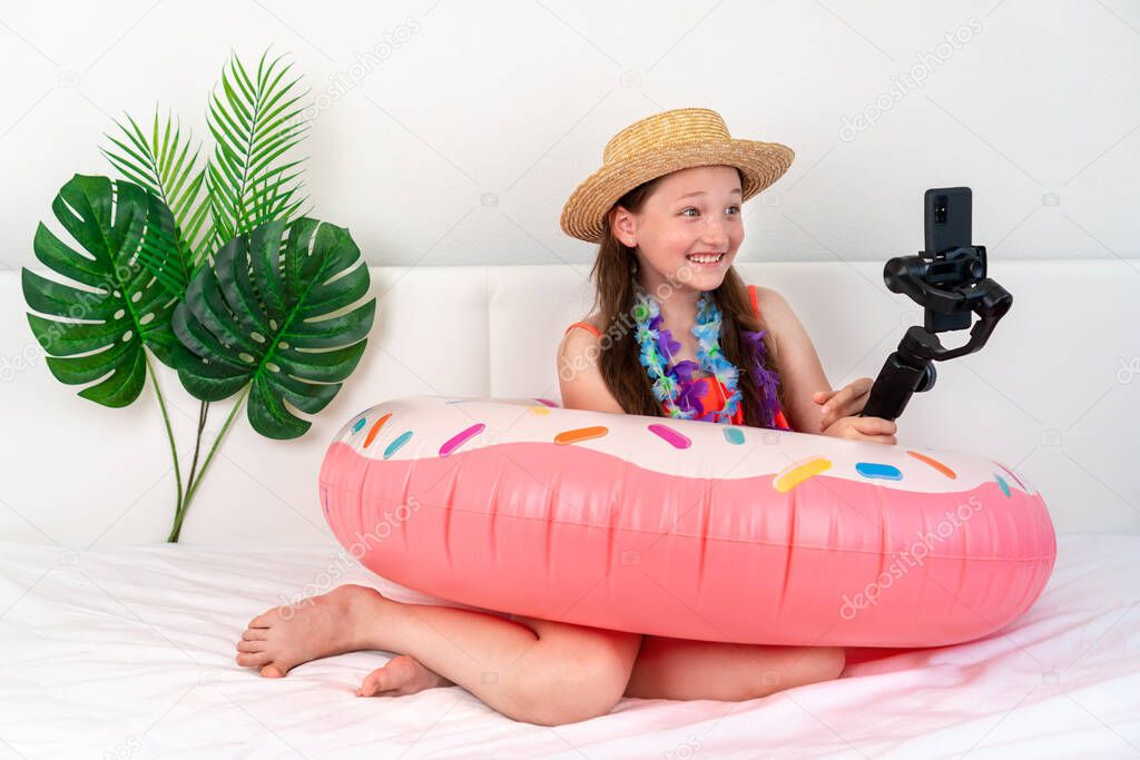 Little girl blogger imitates vacation at home quarantine and shoots video on the phone. Domestic tourism. Coronavirus situation in tourism industry. Quarantine Stay at home. Isolation