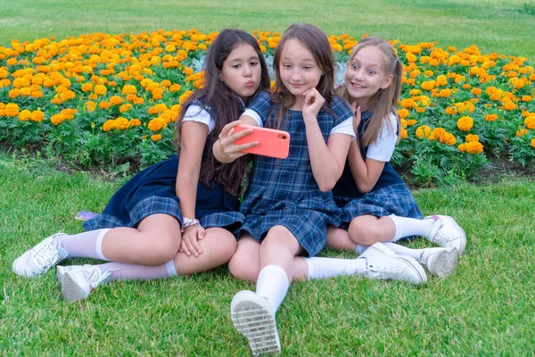 Tres chicas adolescentes toman un teléfono selfie en un día soleado y se ríen. Emociones y nuevas tecnologías — Foto de Stock